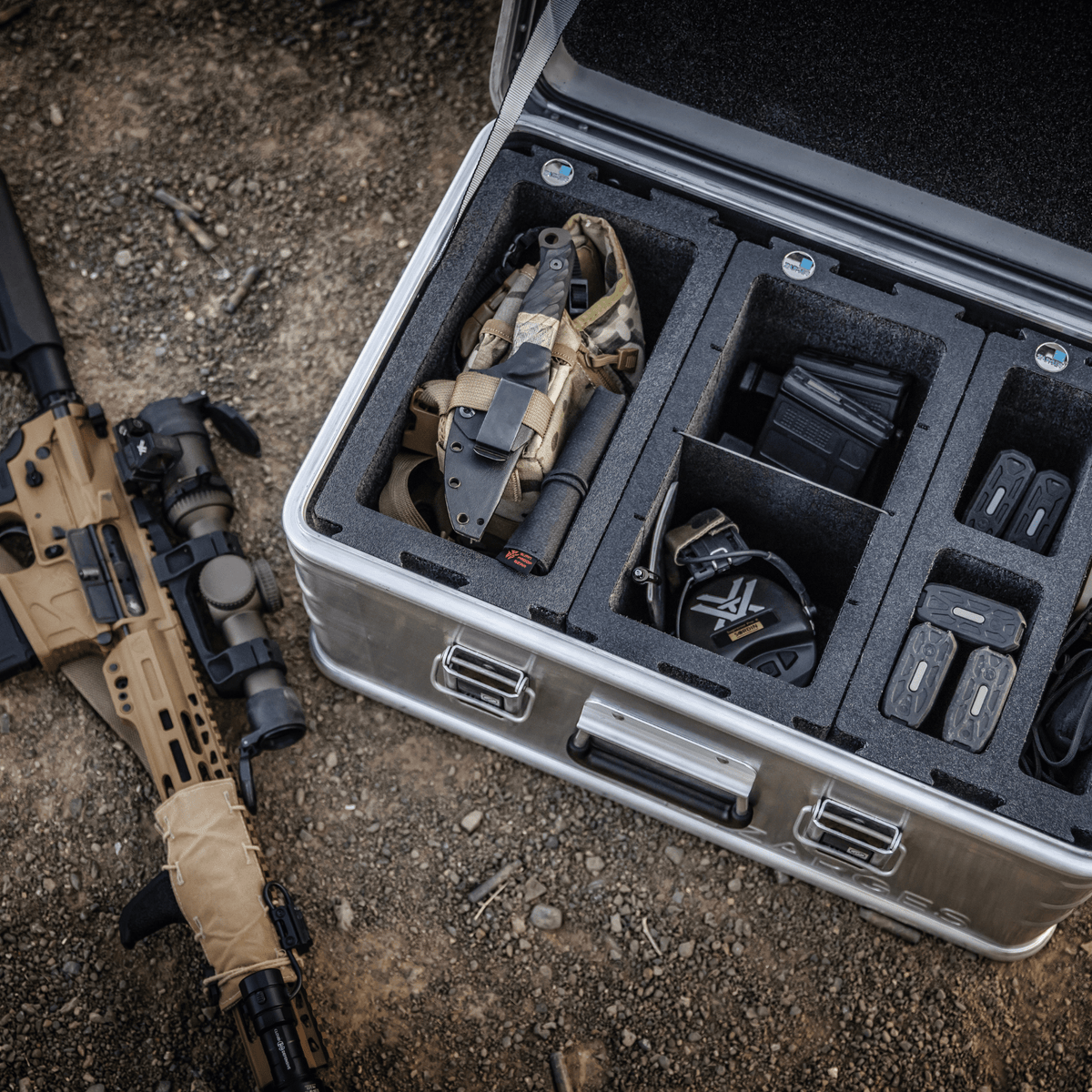 ZARGES Chameleon Case open on rocky ground, foam modules holding a holster, earmuffs and magazines
