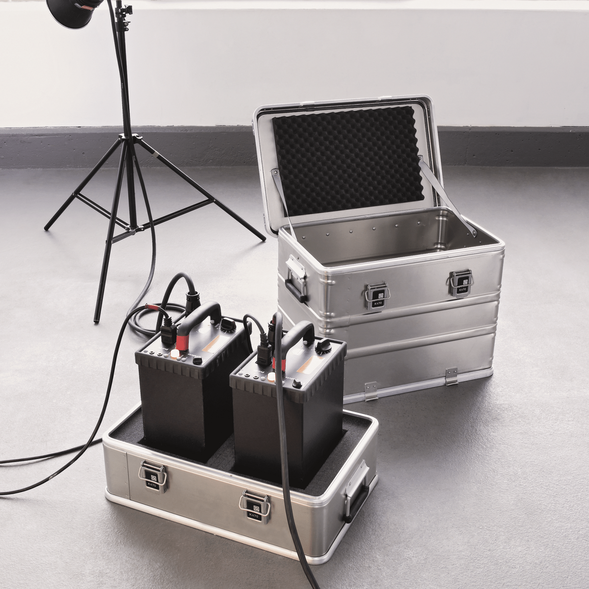 ZARGES K470-Plus Hood Case with the hood open beside its base tray holding two studio power packs