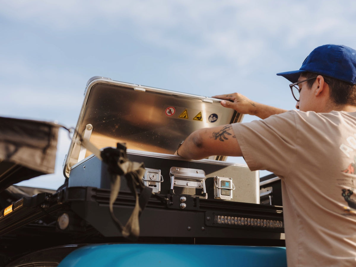 Man lifting the lid of a ZARGES K470-40810 case mounted on a vehicle roof rack