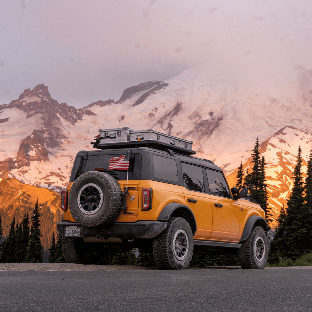 Teal SUV on a pine-covered trail with a ZARGES K470-31011686 case on its roof rack