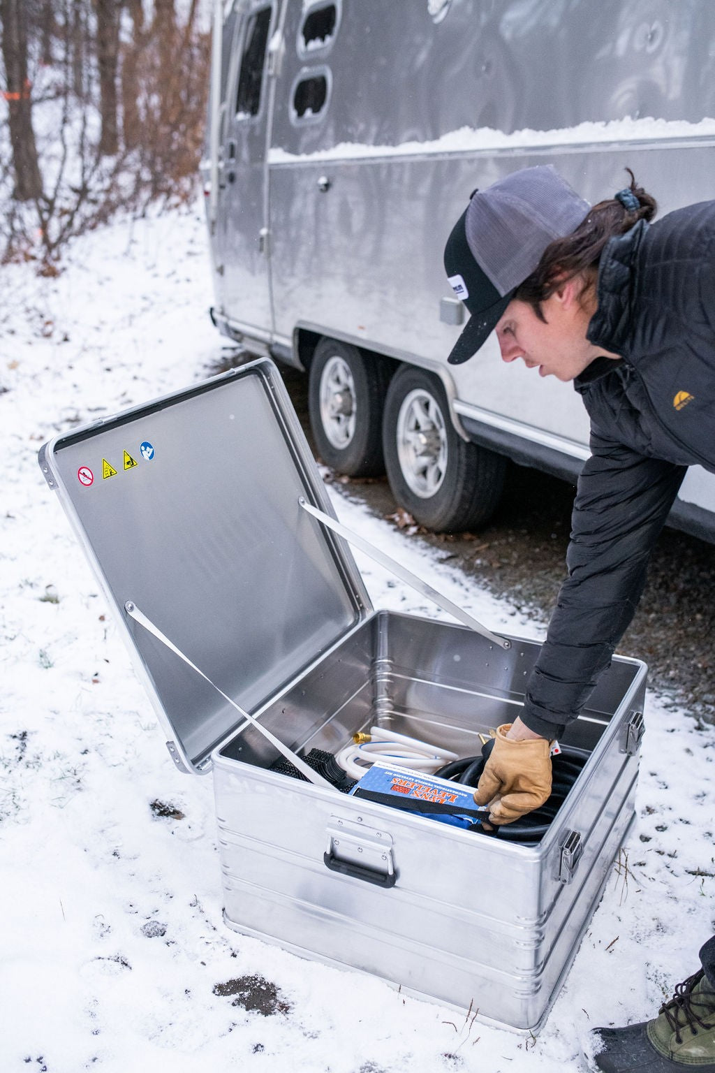ZARGES K470-40842 case open in the snow while a man in work gloves packs cables and gear inside