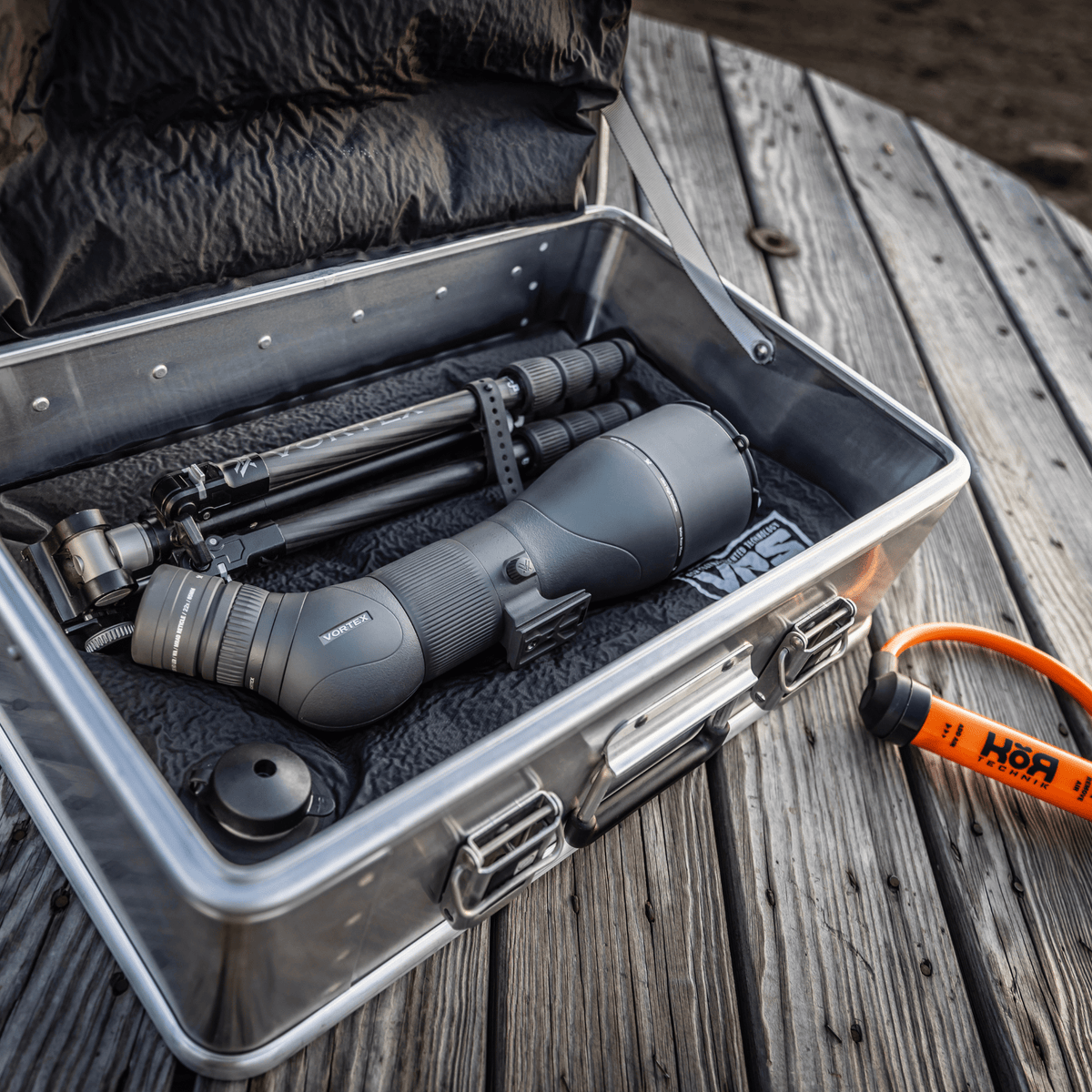 Spotting scope and tripod packed in an open ZARGES Small Pistol & Gear Case on a wooden deck
