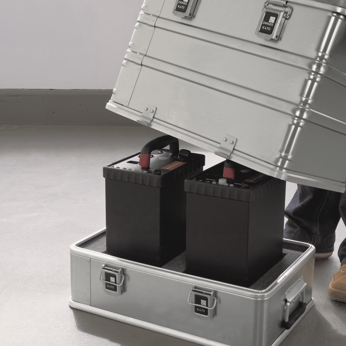 Hood of a ZARGES K470-Plus Hood Case being lowered over two power packs on its base tray