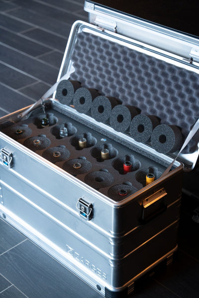 ZARGES 12 Bottle Wine Case open on a tiled floor, bottle tops in foam pockets, foam collars in the lid