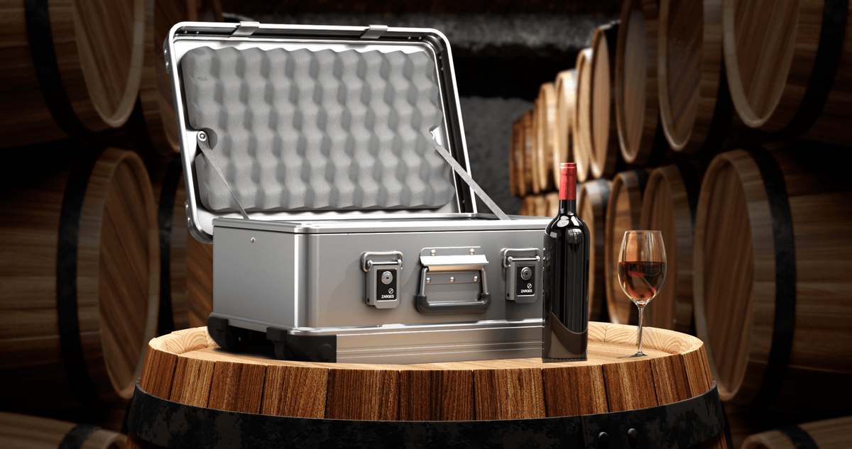 ZARGES 3 Bottle Wine Case open on an oak barrel beside a wine bottle and a glass of red