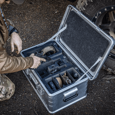 Kneeling man packs gear into ZARGES Chameleon Module - Double Wide with Dividers inside an open case
