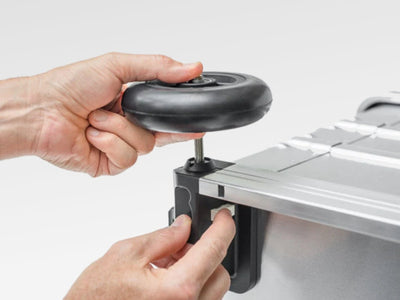 Hands fitting a K424 XC 5 inch wheel (41818) onto the axle of a ZARGES aluminum case