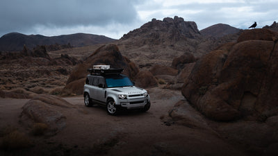 Wide view of a silver SUV carrying a ZARGES K470-380031 case on its roof among red rock formations