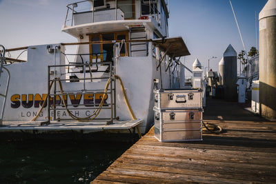 Two stacked ZARGES K470-40564 cases on a wooden dock beside a moored sportfishing boat