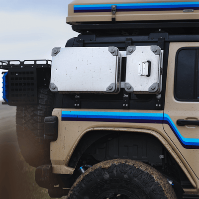 ZARGES K470-40810 aluminum case mounted on the side of a muddy tan off-road vehicle beside a second case