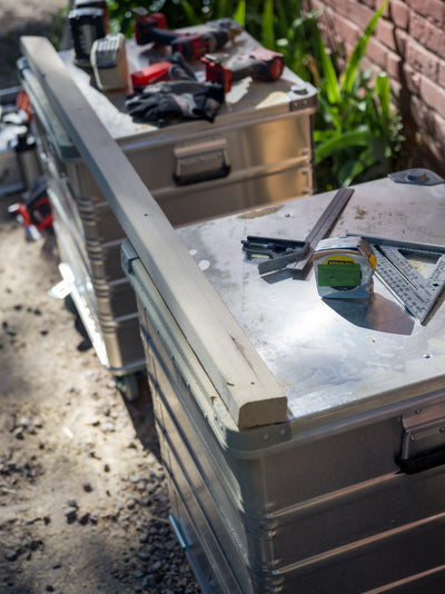 ZARGES K470-40836 aluminum cases used as an outdoor workbench, holding a level, square, tape and power tools