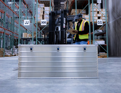 ZARGES K470-40876 large aluminum case on a warehouse floor in front of a worker with a clipboard