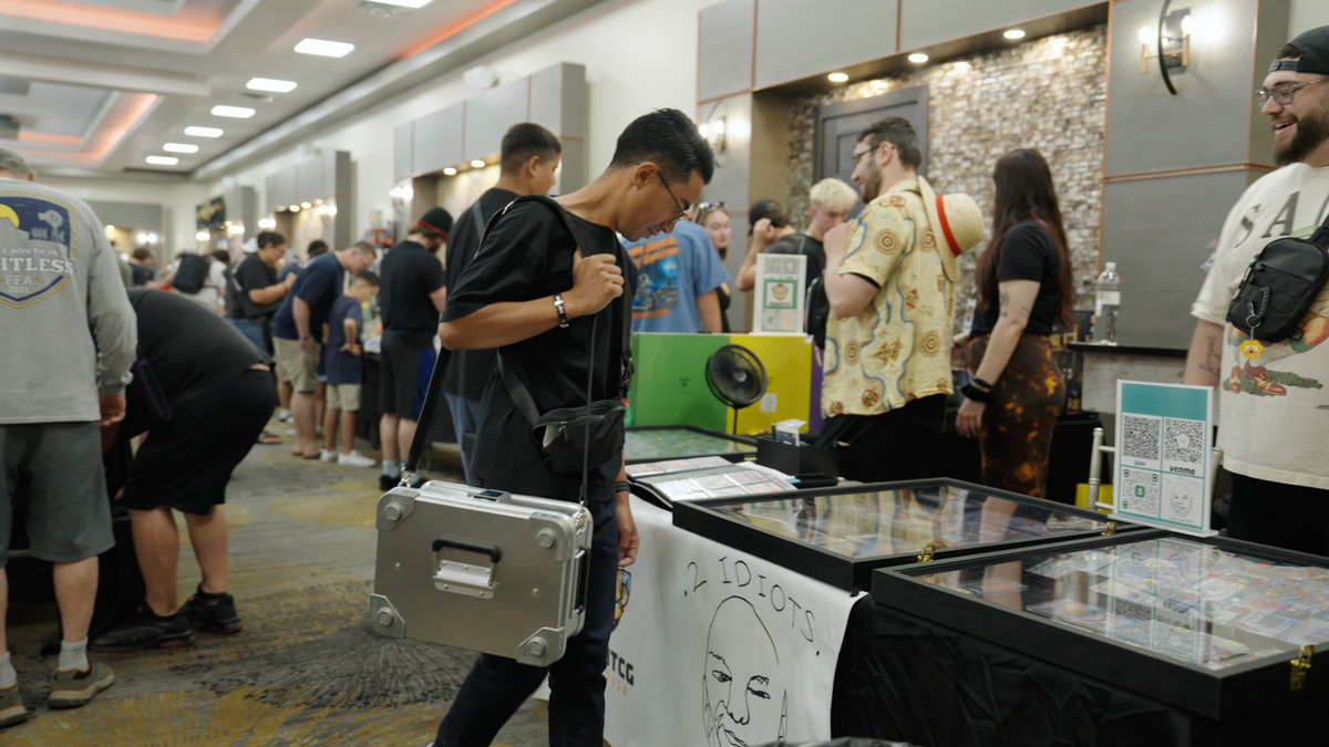 Man on a busy convention floor carrying an aluminum case on the ZARGES Leather Shoulder Strap