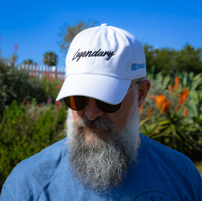 Bearded man in sunglasses wearing the white ZARGES Legendary 47' Hat in a sunny garden
