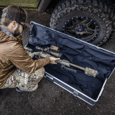 Man in camo lays a scoped rifle on the KOR cushions inside an open ZARGES Single Long Rifle KOR Kit case